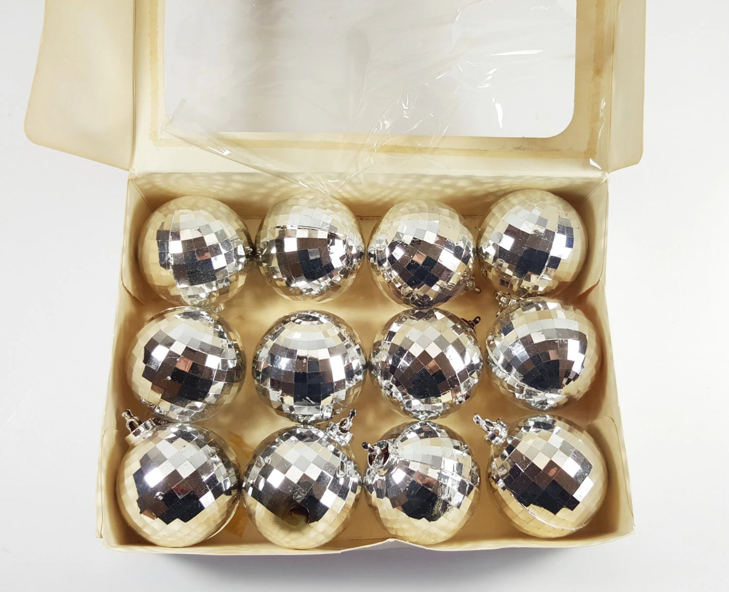Box of silver disco ball ornaments on a white background