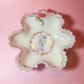 Decorative milk glass dish with floral design on a pink background
