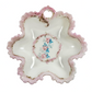 Decorative ceramic plate with pink rim and floral center on a white background