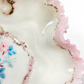 Close-up of a decorative ceramic plate with pink floral design and gold accents.