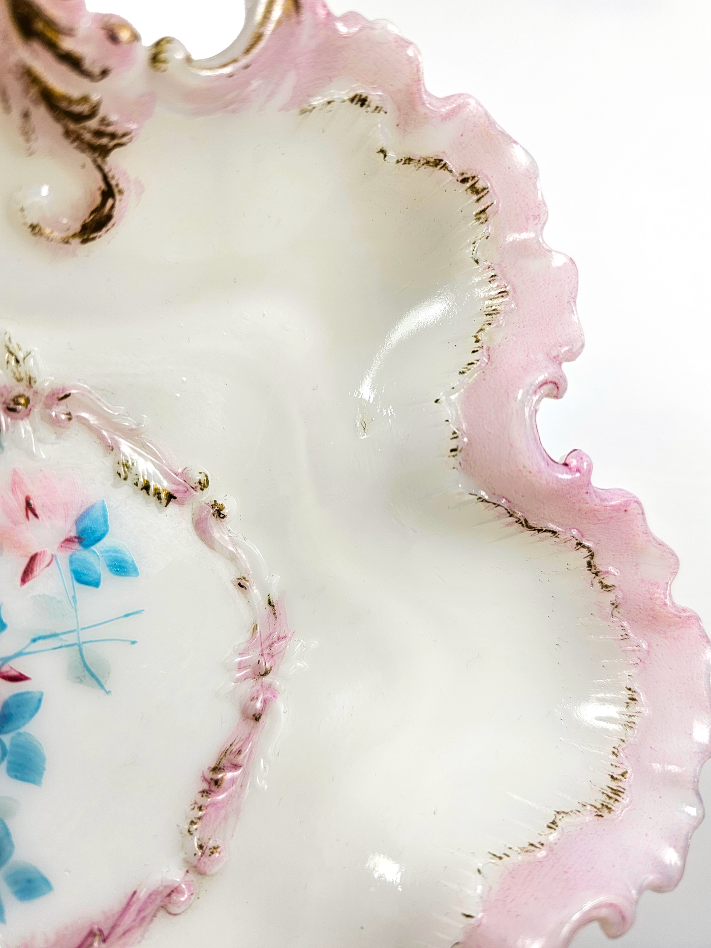 Close-up of a decorative ceramic plate with pink floral design and gold accents.