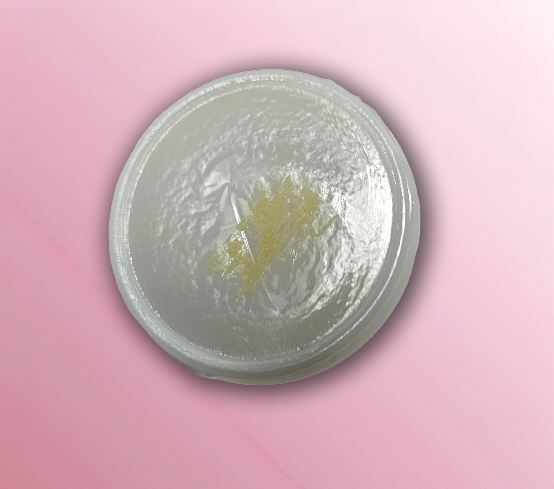 Interior lid of a milk glass candy container on a pink background
