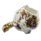 Decorative ceramic flower holder with gold accents and floral patterns on a white background