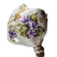 Decorative ceramic flower holder with gold accents and floral patterns on a white background