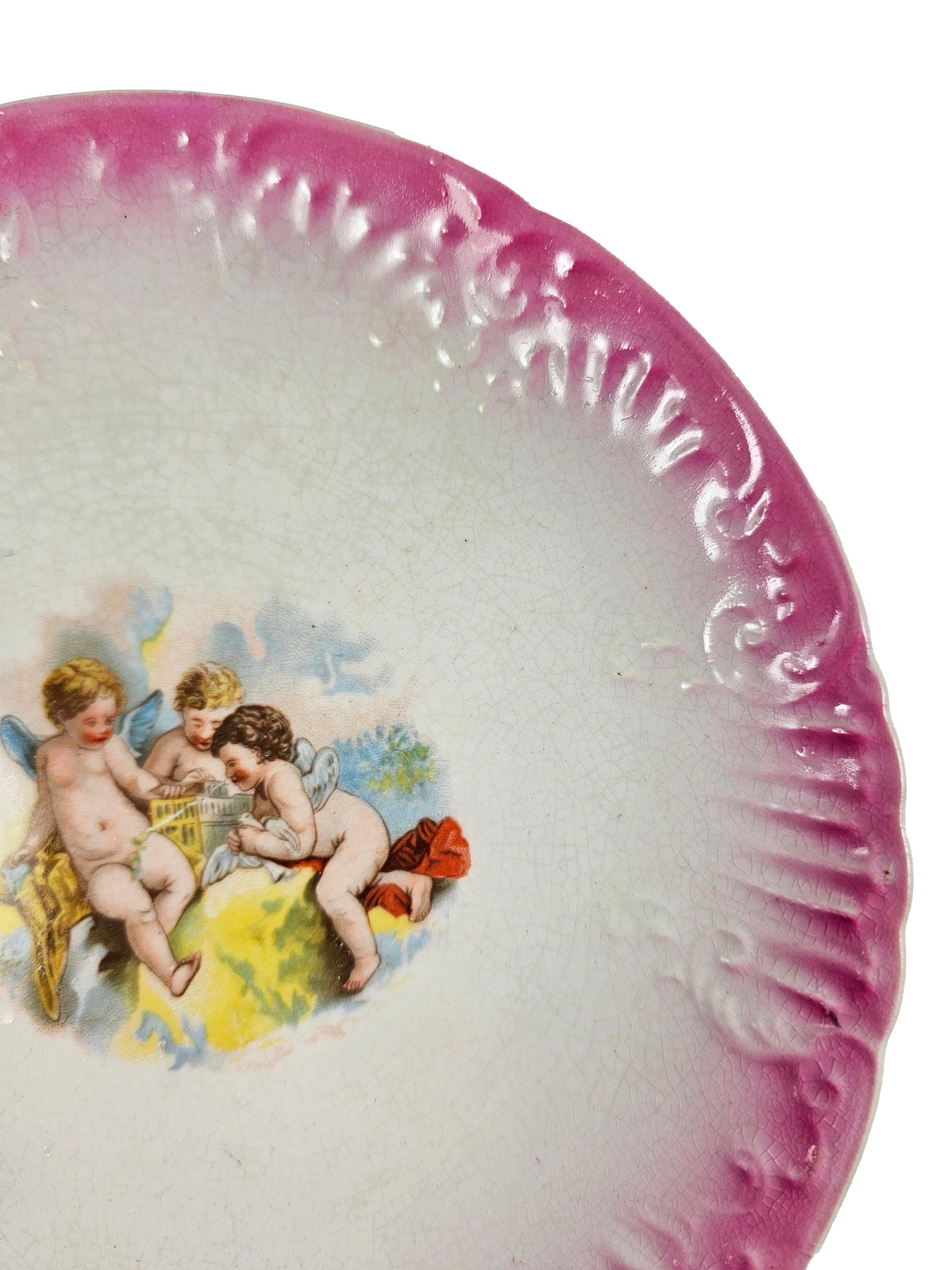 Decorative plate with cherub design and pink rim on a white background