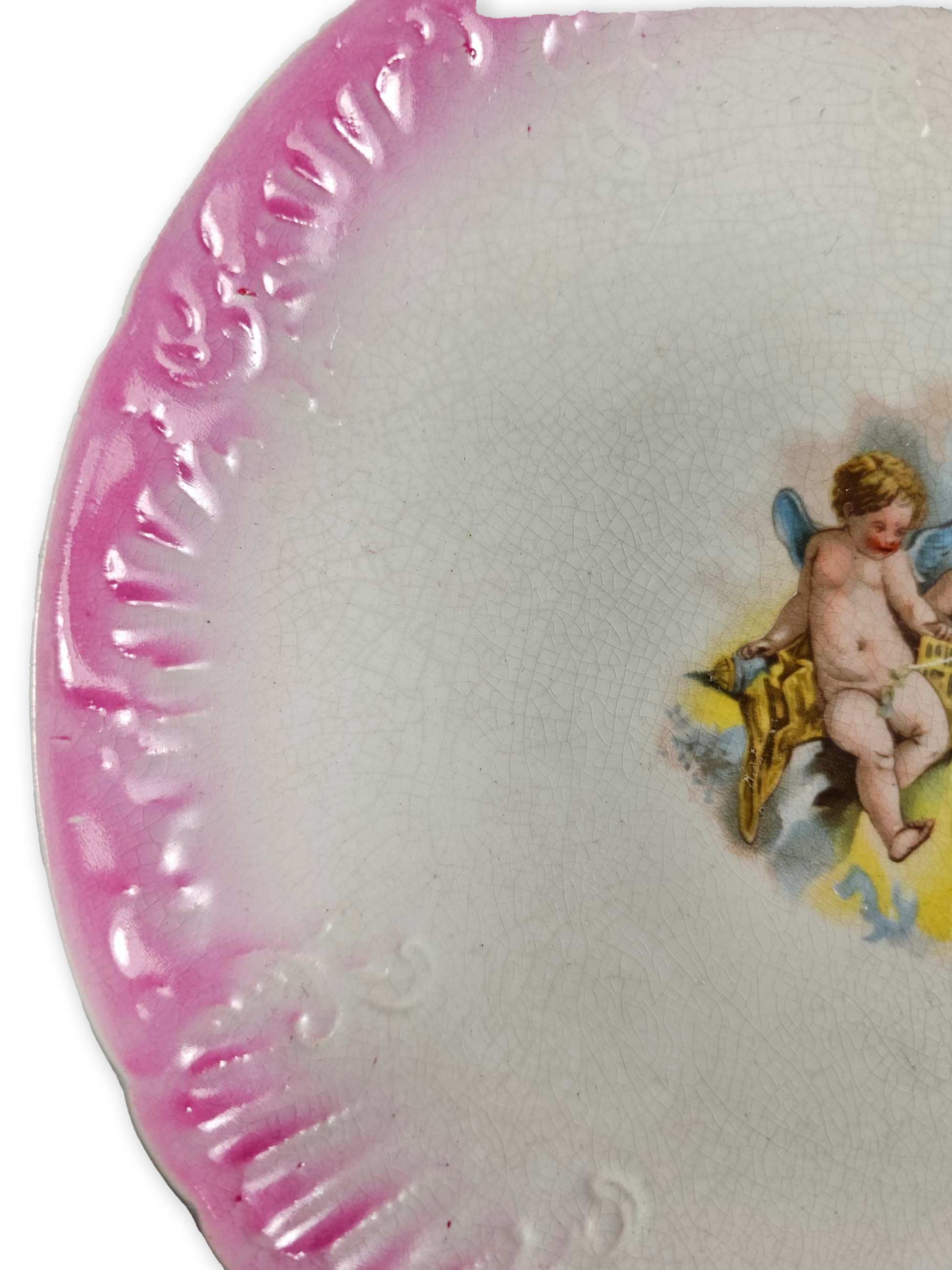 Decorative plate with pink rim and cherub design on a white background