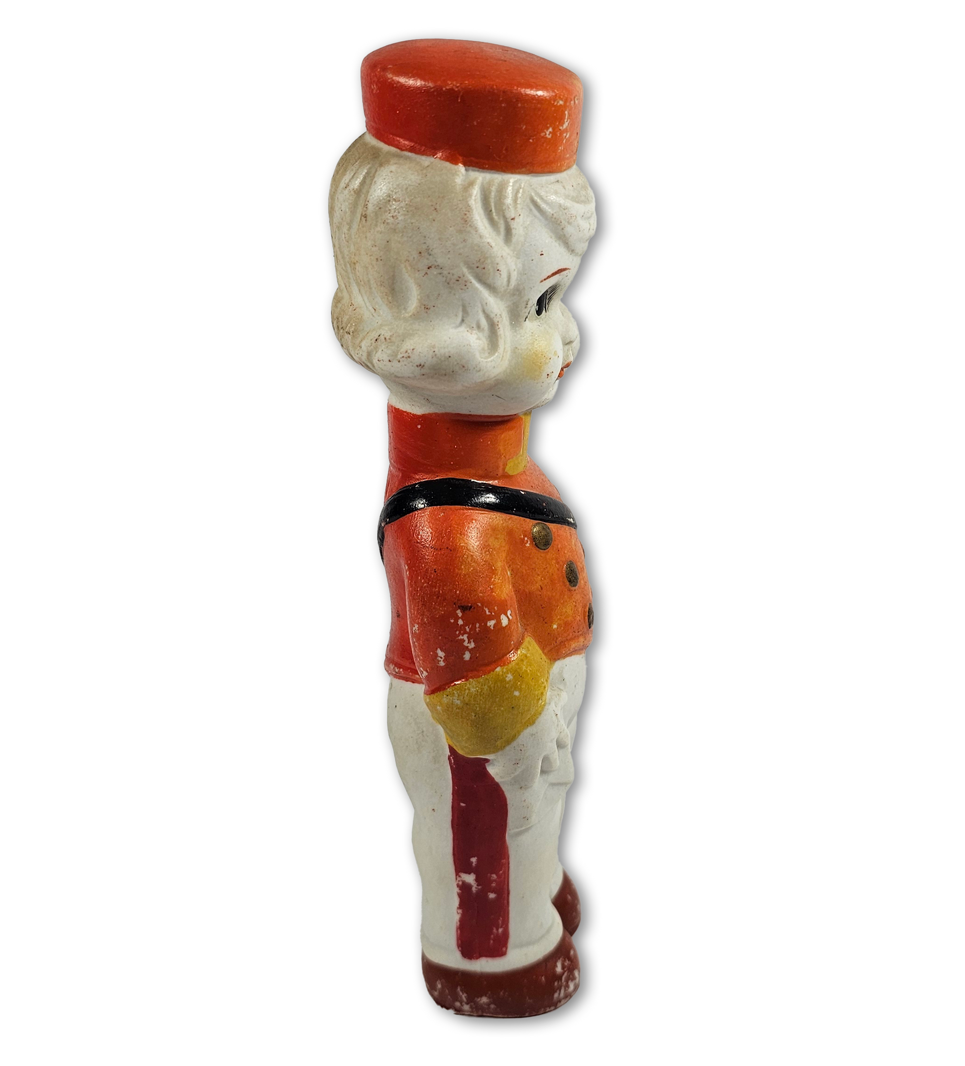 Vintage-style figurine of a boy with a red cap and orange shirt on a white background