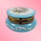 Blue decorative box with floral design on a pink background