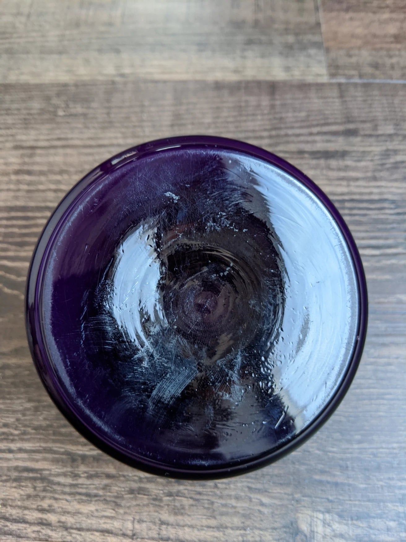 Purple glass roumd box on a wooden surface