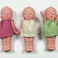 Five small dolls in colorful dresses lined up on a white background