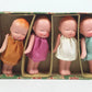 Five small dolls in colorful dresses inside a decorative box on a white background