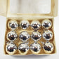 Box of silver disco ball ornaments on a white background