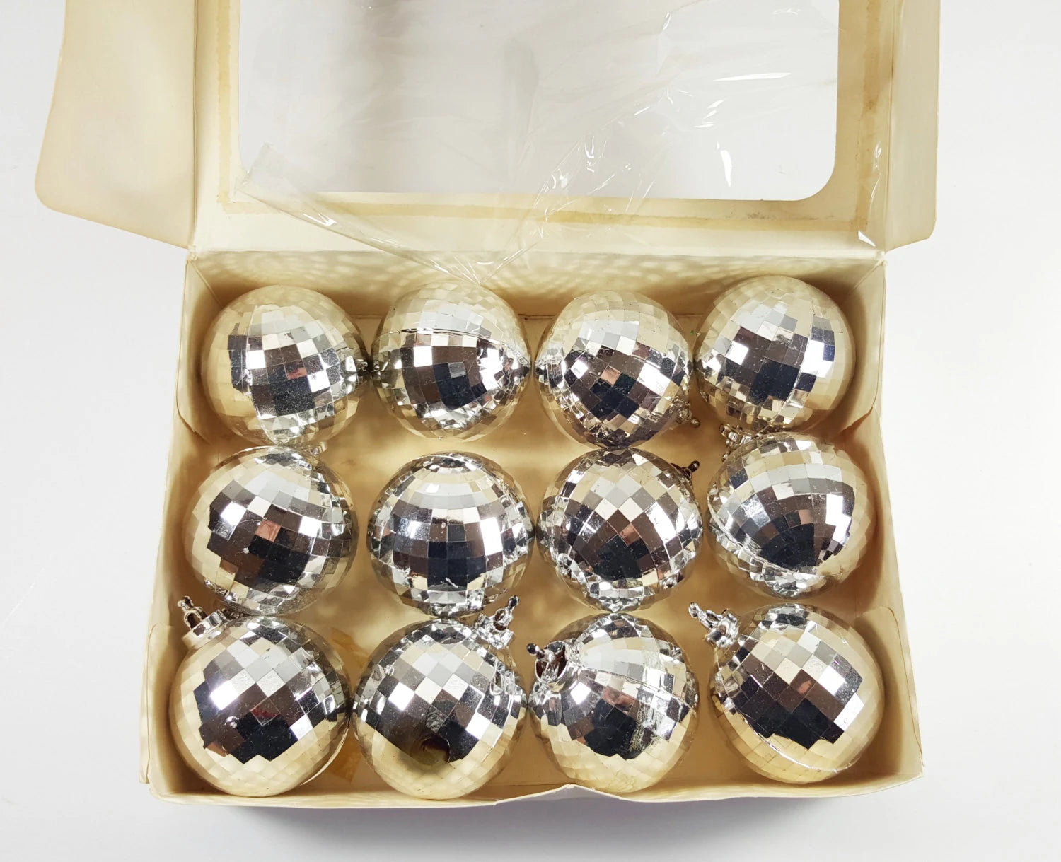 Box of silver disco ball ornaments on a white background