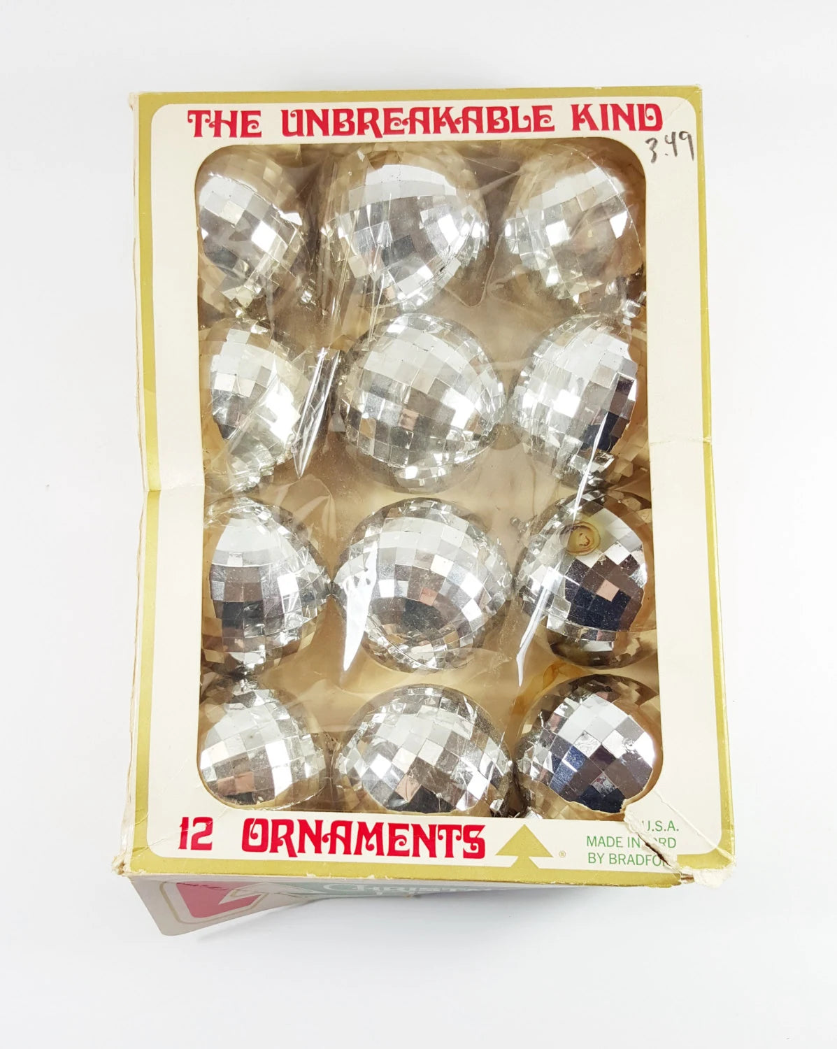 Box of clear Christmas ornaments labeled 'The Unbreakable Kind' on a white background