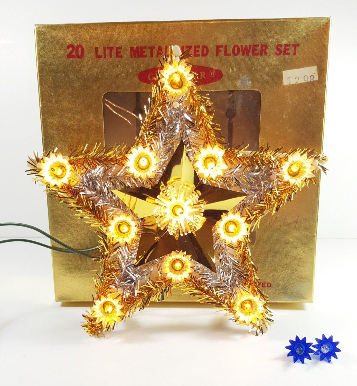 Decorative star-shaped lights in front of a gold box labeled '20 Lite Metalized Flower Set'.